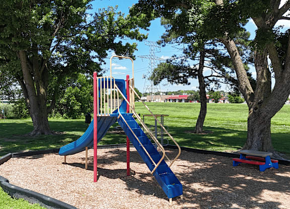 A playground with a blue slide and a red and yellow structure.