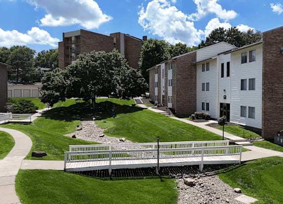 A white building with a brown roof is surrounded by a grassy area and a fence.