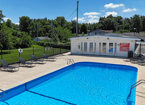 A pool with a blue tiled edge and a white building in the background.