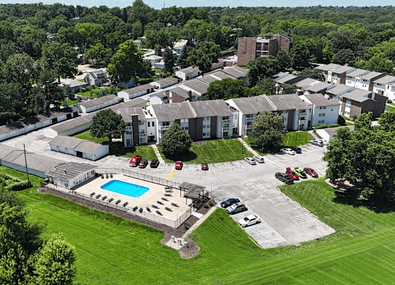A bird's eye view of a residential area with a swimming pool and cars parked in the driveway.