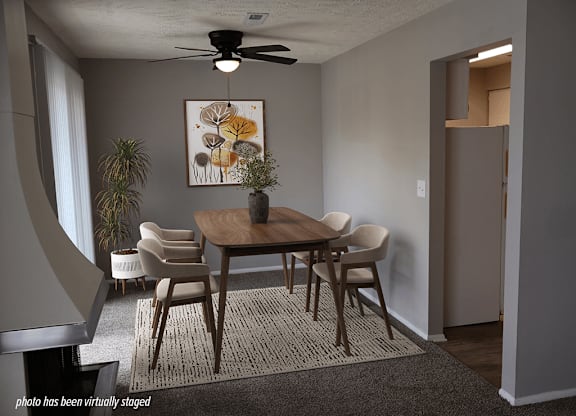 A dining room with a table, chairs, and a ceiling fan.