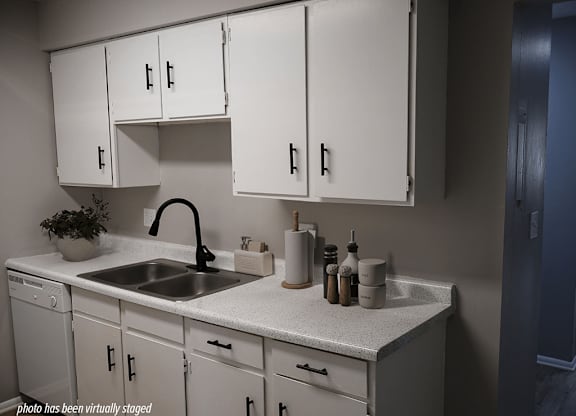 A kitchen with white cabinets and a sink.