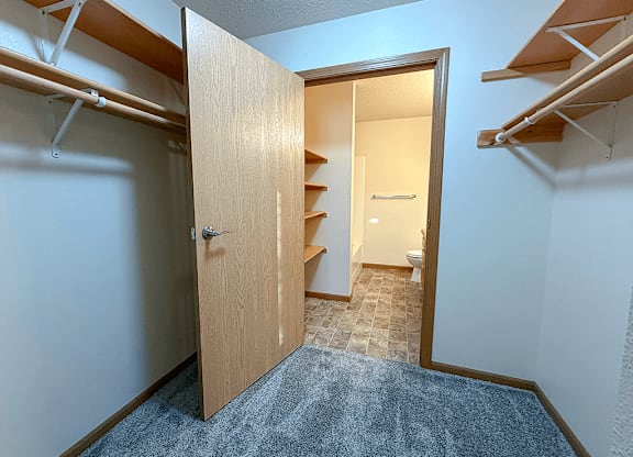 A room with a wooden door leading to a bathroom.
