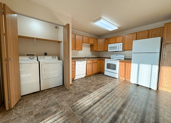 A kitchen with white appliances and wooden cabinets.