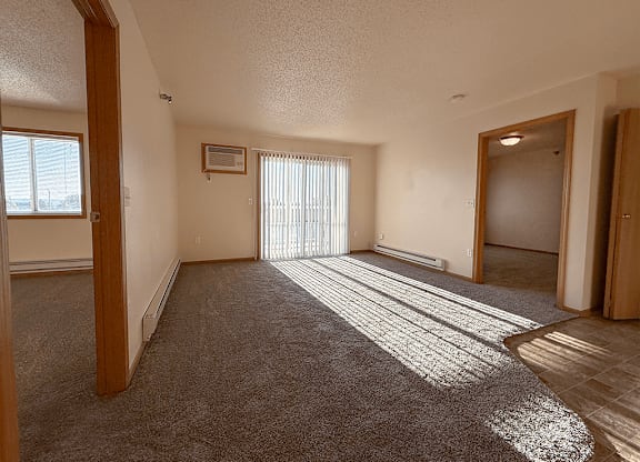 A sunny day with sunlight coming through the blinds in a room with carpet.