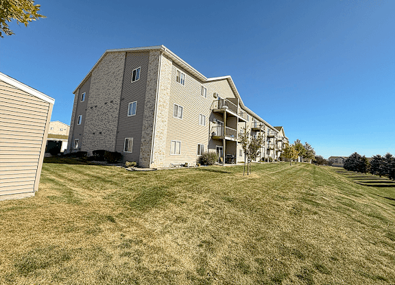 Apartment building with a grassy field in front.