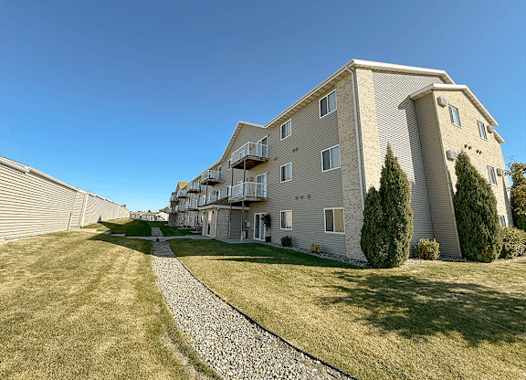 A modern apartment building with a stone pathway leading to the entrance.