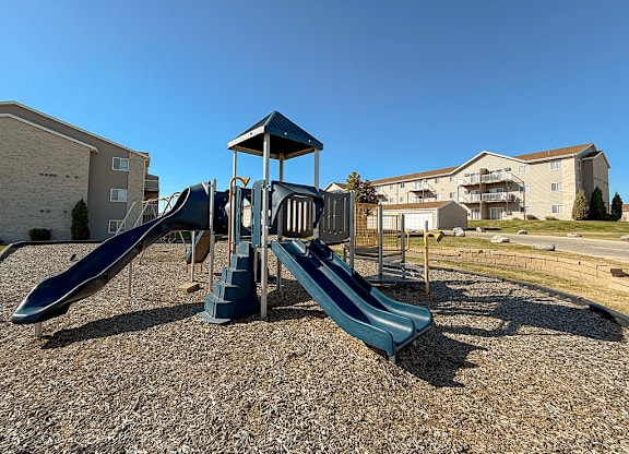 A playground with a blue slide and a wooden structure.