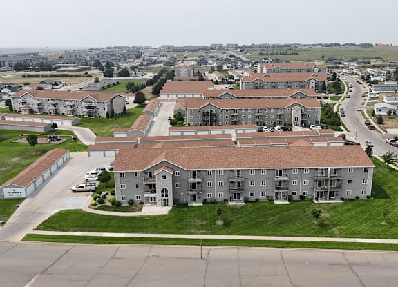 A large apartment complex with a parking lot in front.