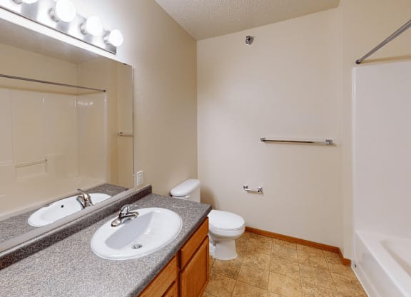 A bathroom with a toilet, sink, and mirror.