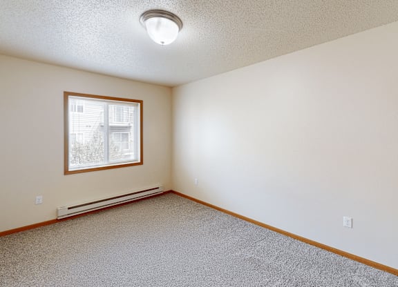 A room with a window and a carpeted floor.