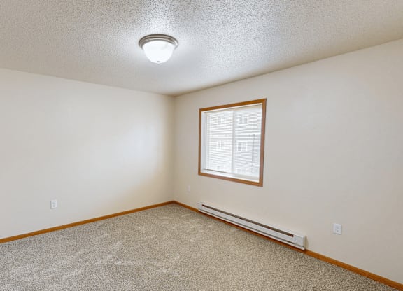 A room with a window and a carpeted floor.
