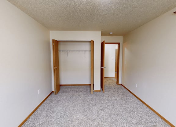 A room with a carpeted floor and two open doors.