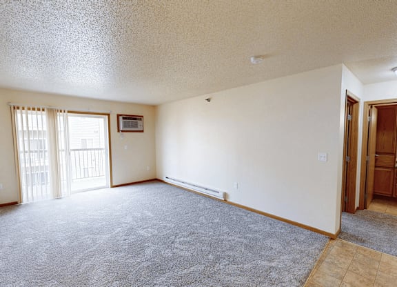 A room with a carpeted floor and a window with blinds.