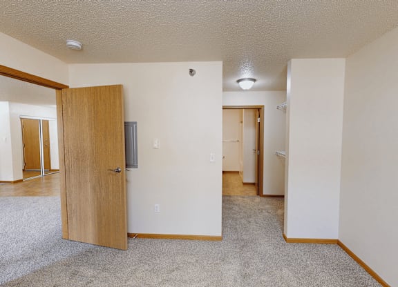 A room with a carpeted floor and a wooden door.