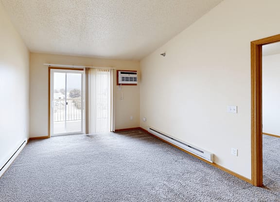 A sparsely furnished room with a sliding glass door.