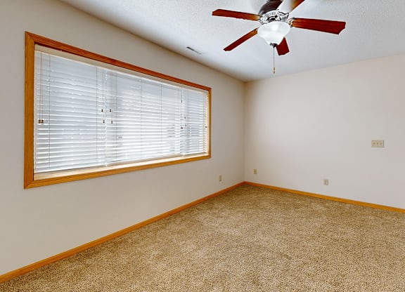 A room with a ceiling fan and a window with blinds.