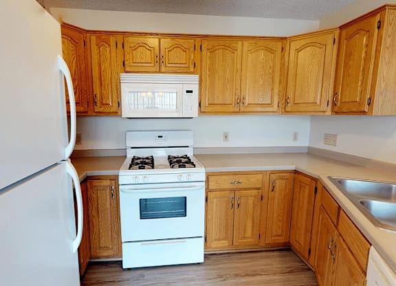 A kitchen with wooden cabinets and a white stove.