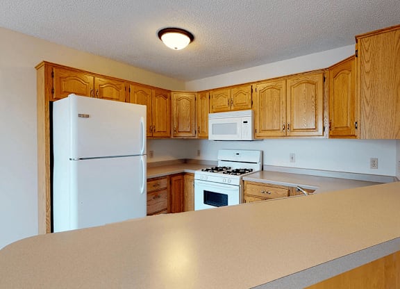 A kitchen with white appliances and wooden cabinets.