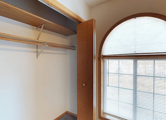 A white wall with a wooden door and a window with blinds.