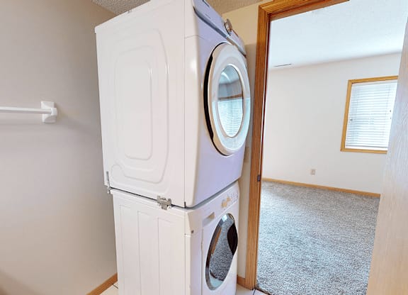A white washing machine and dryer stacked on top of each other in a laundry room.
