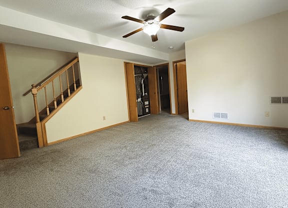 A room with a carpeted floor and a ceiling fan.