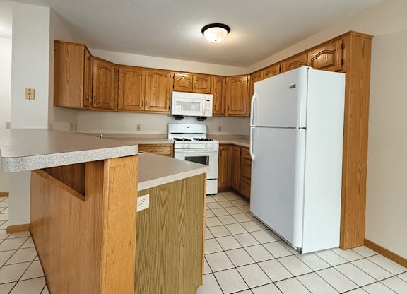 A kitchen with white appliances and wooden cabinets.