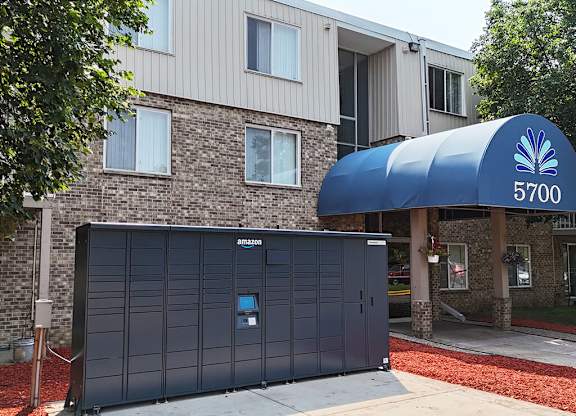A grey Amazon storage unit is in front of a brick building.