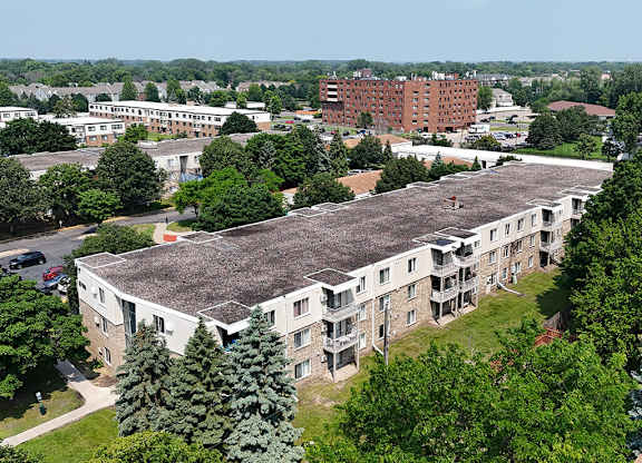A large building with a grey roof is surrounded by trees.