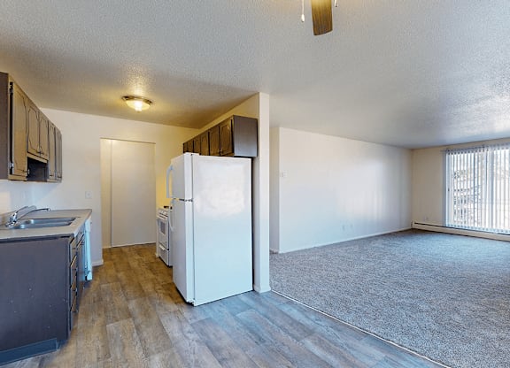 A kitchen with a white refrigerator and wooden floors.