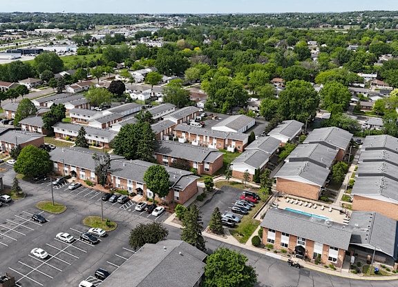 A bird's eye view of a residential area with houses, cars, and trees.