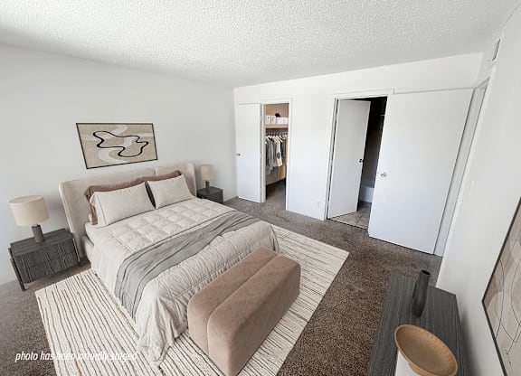 A bedroom with a large bed and a wardrobe in the background.