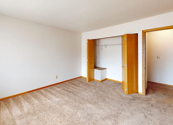 A room with a carpeted floor and a white wall with a wooden door.
