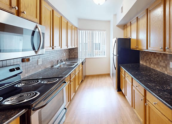 A kitchen with wooden cabinets and a black counter top.