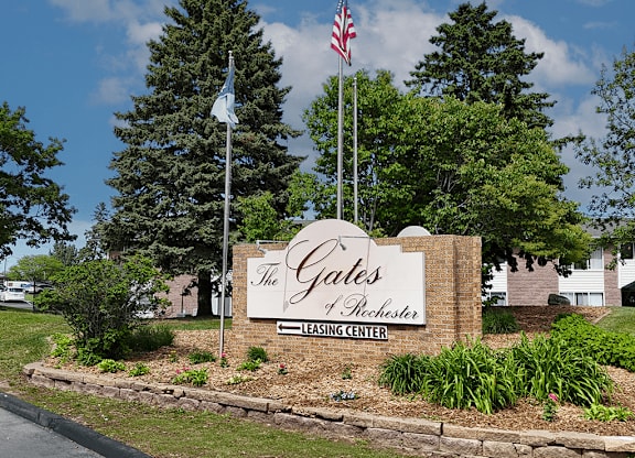 The Gates Leasing Center sign is in front of a building and trees.