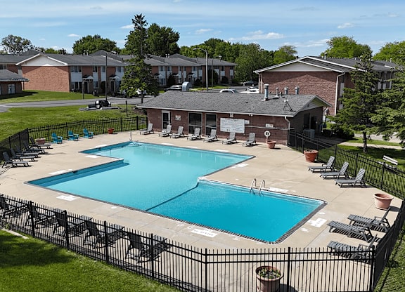 A black fence surrounds a blue swimming pool.