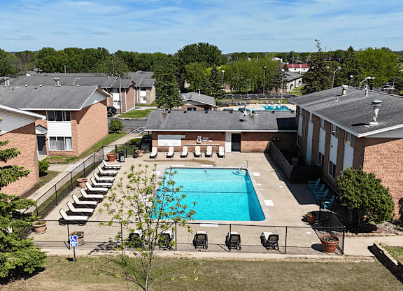 A pool surrounded by chairs and trees.