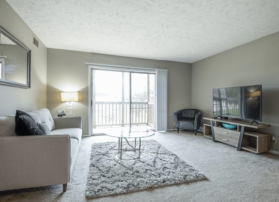 a living room with a couch and a tv and a balcony