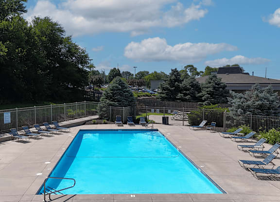A large swimming pool surrounded by trees and chairs.