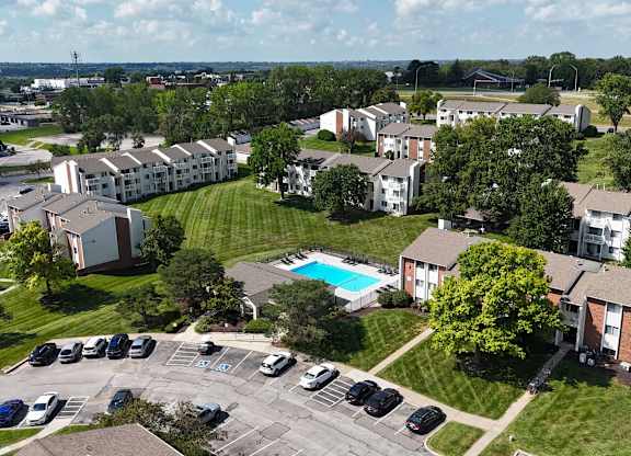 A large apartment complex with a pool in the middle of the parking lot.