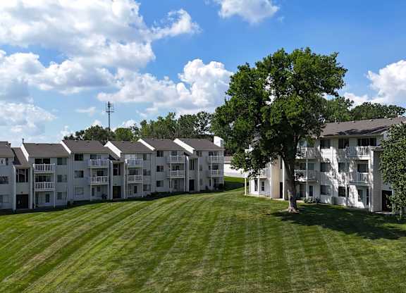 A large grassy field in front of apartment buildings.