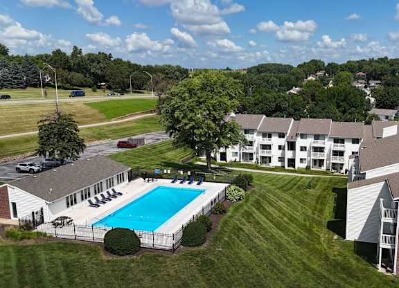 A swimming pool is surrounded by a fence and houses.