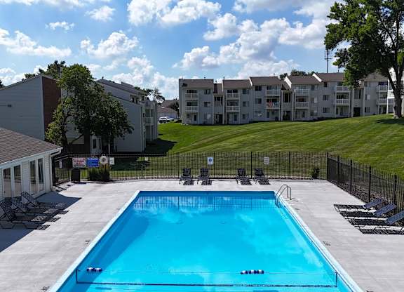 A swimming pool surrounded by a black fence and chairs.