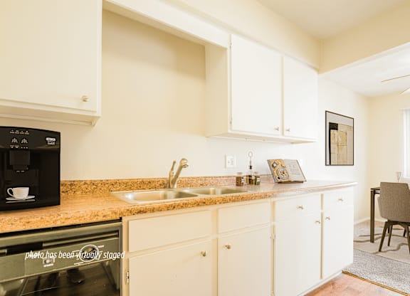 A kitchen with white cabinets and a black microwave.