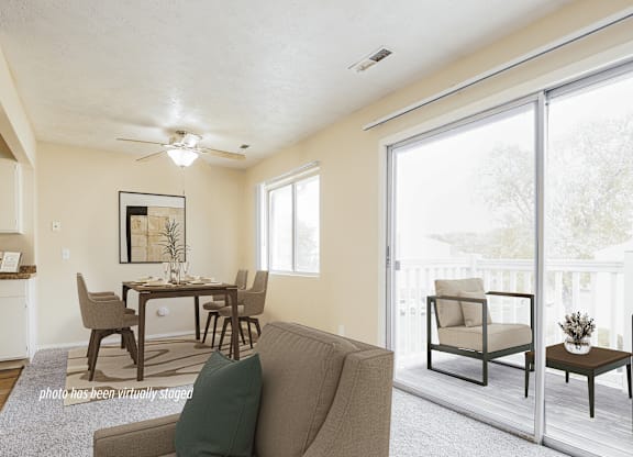 A living room with a brown couch and a dining table with chairs.