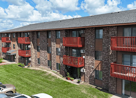 A building with balconies and a car parked in front.