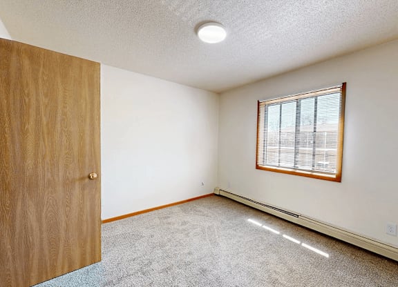 A room with a wooden door and a window with blinds.