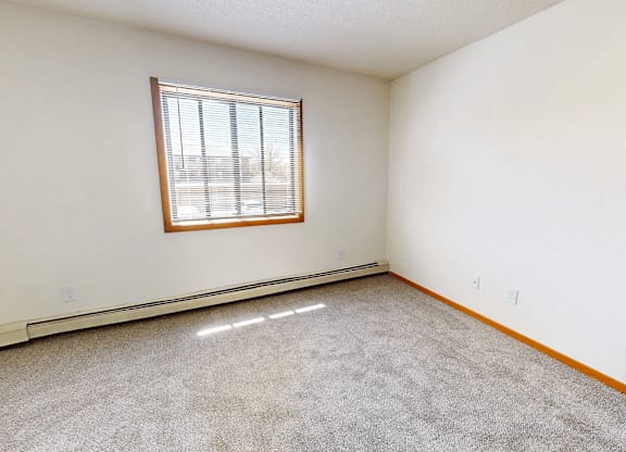 A room with a window and carpeted floor.