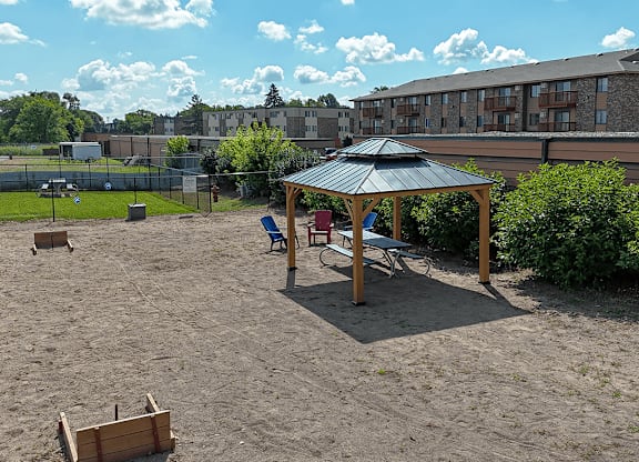 A sandy playground area with a wooden structure and a black umbrella.