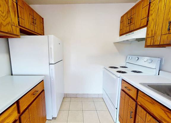 A kitchen with white appliances and wooden cabinets.